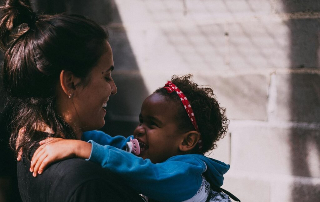 A mother and daughter share a joyful embrace outside, exuding warmth and affection.
