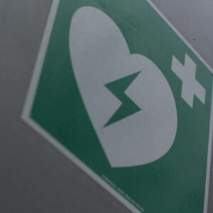 Green first aid sign featuring a broken heart and cross symbol for medical emergency awareness.